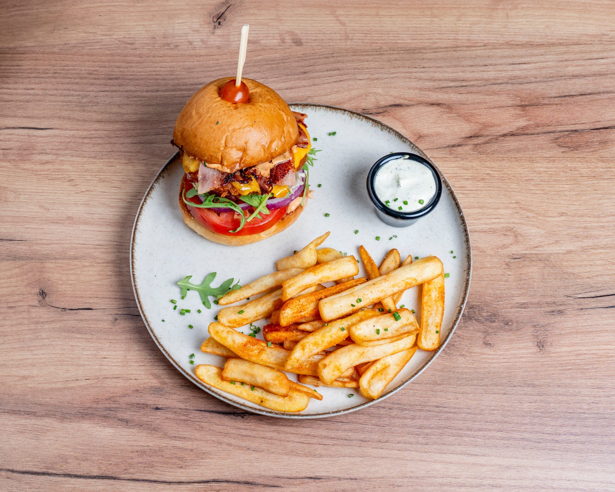 A burger and fries on a plate, with a side of garlic mayo dip