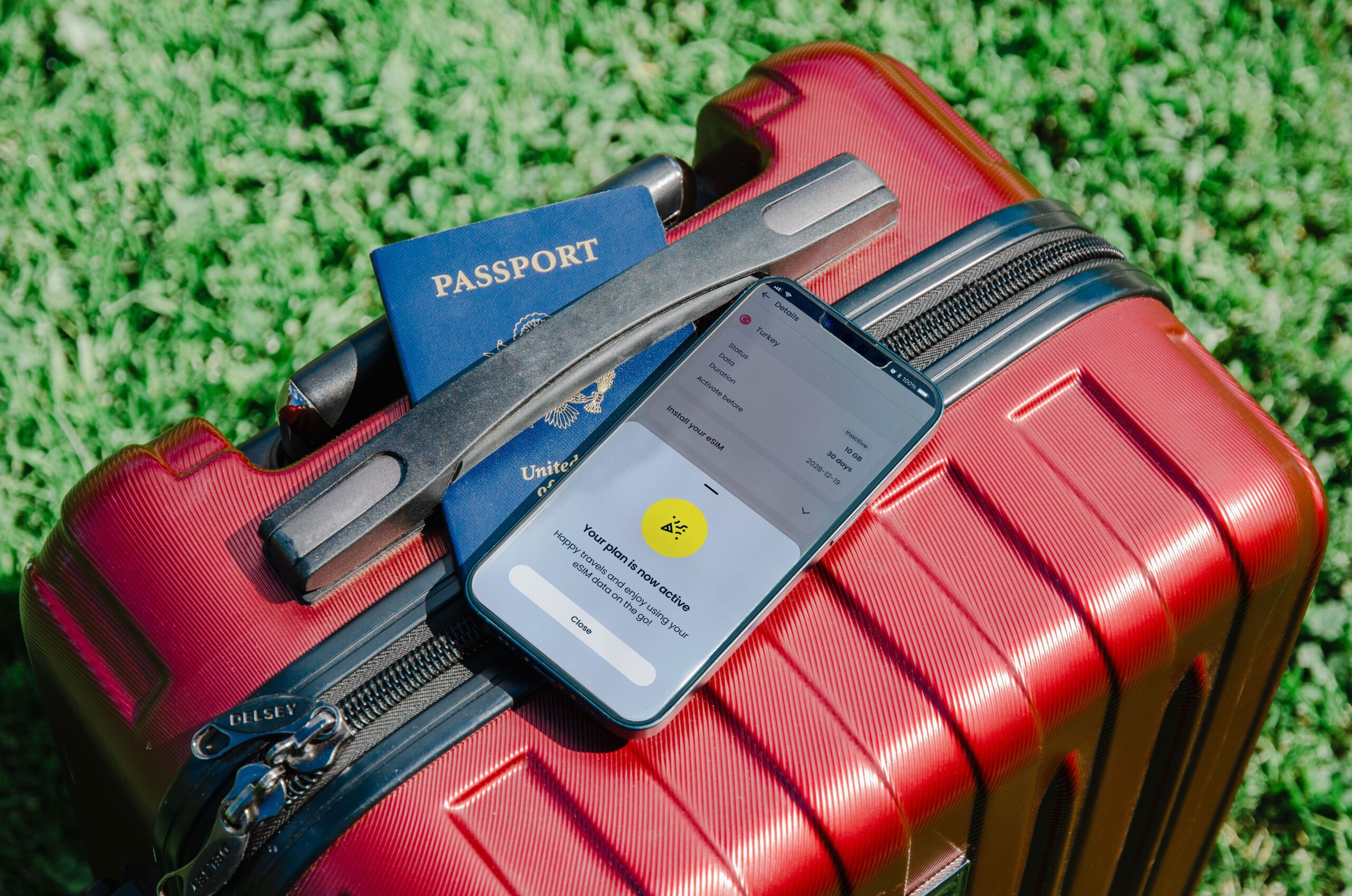 A suitcase with a passport and mobile phone on top